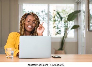 African American Woman With Laptop Surprised With An Idea Or Question Pointing Finger With Happy Face, Number One