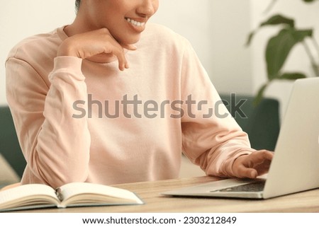 African American woman with laptop at wooden table indoors, closeup