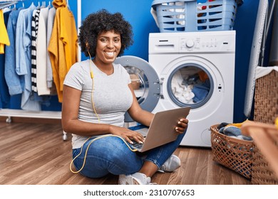 African american woman listening to music waiting for washing machine at laundry room - Shutterstock ID 2310707653