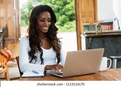 African American Woman With Long Hair Working At Computer At Desk At Home