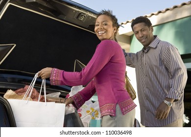 African American Woman With Man Loading Shopping Bags In Car