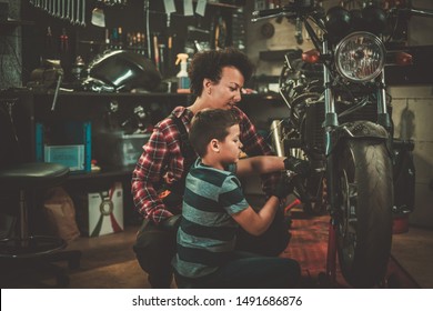 African American Woman Mechanic And Boy Helper Repairing A Motorcycle In A Workshop