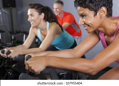 An African American Woman And Middle Aged Friends On Exercise Bikes At A Gym