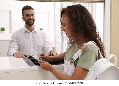 African American woman with money at cash department window in bank. Currency exchange - Shutterstock ID 2075832469