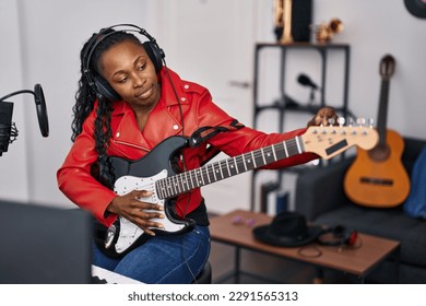 African american woman musician playing guitar at music studio - Powered by Shutterstock