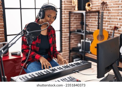 African american woman musician playing piano at music studio - Powered by Shutterstock