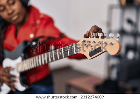 African american woman musician playing guitar at music studio