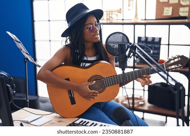 African american woman musician singing song playing classical guitar at music studio - Powered by Shutterstock