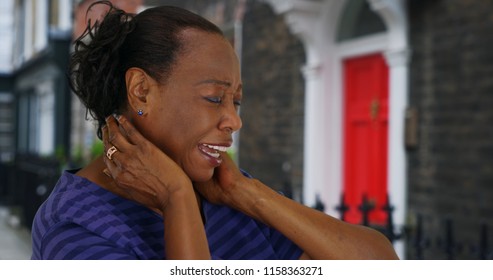 African American Woman With Neck Pain Standing Outside Home