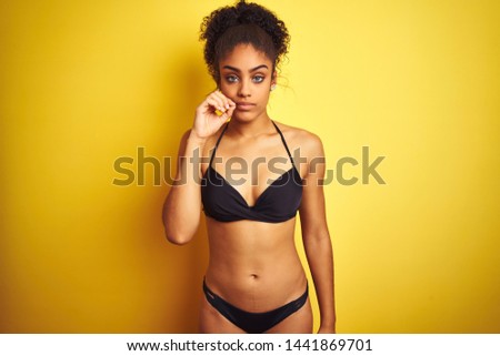 African american woman on vacation wearing bikini standing over isolated yellow background mouth and lips shut as zip with fingers. Secret and silent, taboo talking