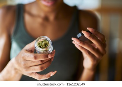 african american woman opening bottle of legal marijuana from dispensary close up