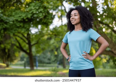 African American woman participating in an outdoor fitness class, standing confidently with hands on hips. The setting is a lush, green park, suggesting a healthy and active lifestyle. - Powered by Shutterstock