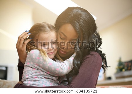 African American woman playing with girl. Woman hugging her adopted daughter.
