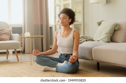 African American Woman  Practice Meditating And Sitting At Home. Calm Female Taking Deep Breath And Relaxing With Eyes Closed. No Stress And Peace Of Mind.