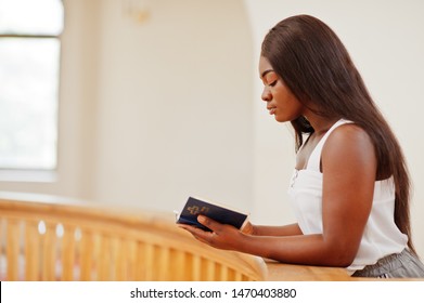 African american woman praying in the church. Believers meditates in the cathedral and spiritual time of prayer. Afro girl with holy bible at hands.