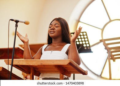African american woman praying in the church. Believers meditates in the cathedral and spiritual time of prayer. Afro girl singing and glorifying God on choruses.