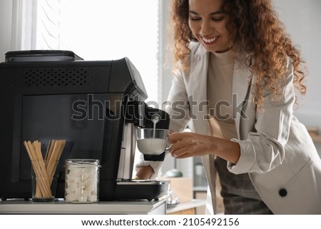 African American woman preparing fresh aromatic coffee with modern machine in office, closeup