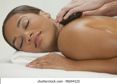 An African American  woman relaxing at a health spa while having a hot stone treatment or massage