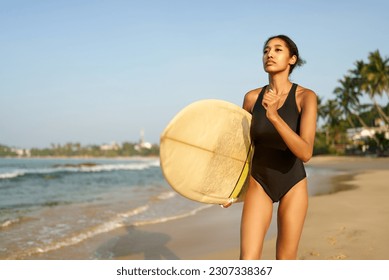 African american woman running with surfboard on ocean beach. Black female surfer with surf board. Pretty multiethnic girl goes on surfing session on tropical location at sunny sunrise. - Powered by Shutterstock