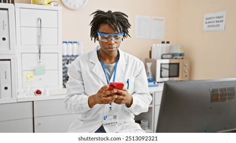 African american woman scientist with dreadlocks wearing safety glasses and lab coat using smartphone in laboratory. - Powered by Shutterstock