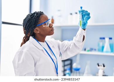 African american woman scientist holding test tube at laboratory - Powered by Shutterstock