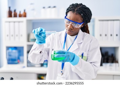 African american woman scientist pouring liquid on test tube at laboratory - Powered by Shutterstock