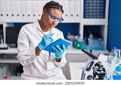 African american woman scientist using touchpad at laboratory - Powered by Shutterstock