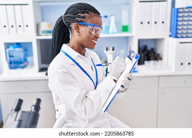 African American Woman Scientist Writing Report Working At Laboratory