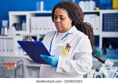 African American Woman Scientist Writing On Clipboard At Laboratory