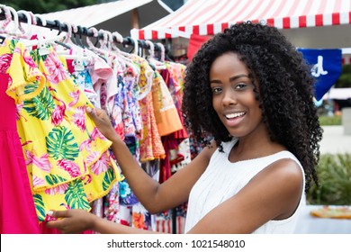 African American Woman Selling Colorful Clothes Outdoors At Typical Traditional Market