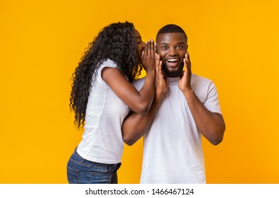 African American Woman Sharing Secret With Her Man, guy is excited, yellow studio background
