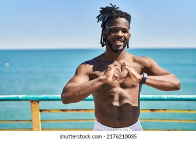 African American Woman Shirtless Doing Heart Gesture With Hands At Seaside