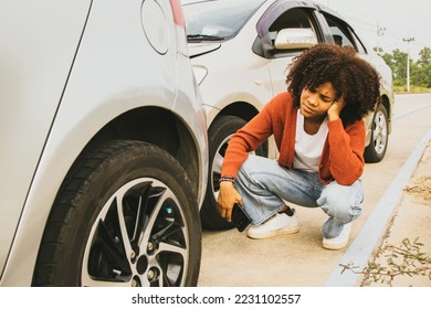 African American woman with shocked expression drove recklessly crashing into the rear of the car and damaging the front Sitting distraught looking at the damage to her car there was no car insurance. - Shutterstock ID 2231102557