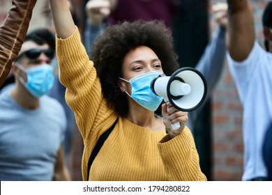 African American woman shouting through megaphone while wearing protective face mask on a anti-racism protest.  - Shutterstock ID 1794280822