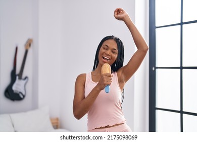 African American Woman Singing Song Using Brush As A Microphone At Bedroom