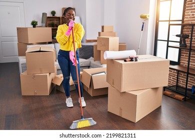 African American Woman Singing Song Using Mop As A Microphone At New Home