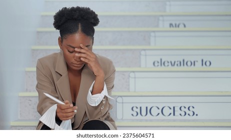 African american woman sitting on staircase with feeling depress after working hard at office. Young businesswoman sitting on stairs having sad and depressed - Powered by Shutterstock