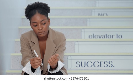 African american woman sitting on staircase with feeling depress after working hard at office. Young businesswoman sitting on stairs having sad and depressed - Powered by Shutterstock