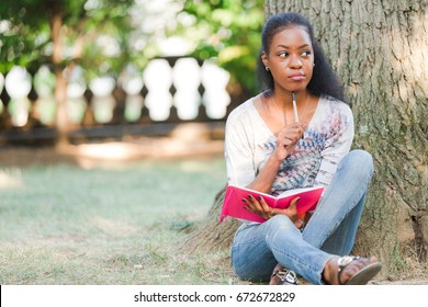 African American Woman Sitting Under Tree With Journal