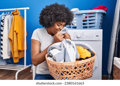 African american woman smelling towel standing at laundry room - Powered by Shutterstock