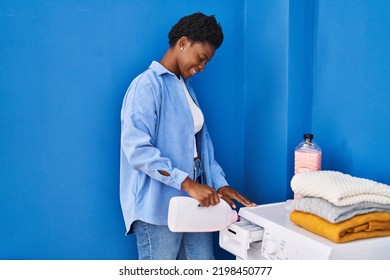 African American Woman Smiling Confident Pouring Detergent On Washing Machine At Laundry Room