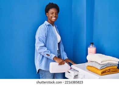 African American Woman Smiling Confident Pouring Detergent On Washing Machine At Laundry Room