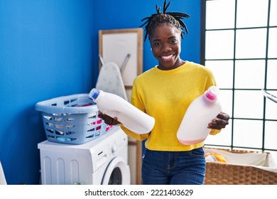 African American Woman Smiling Confident Holding Detergent Bottles At Laundry Room