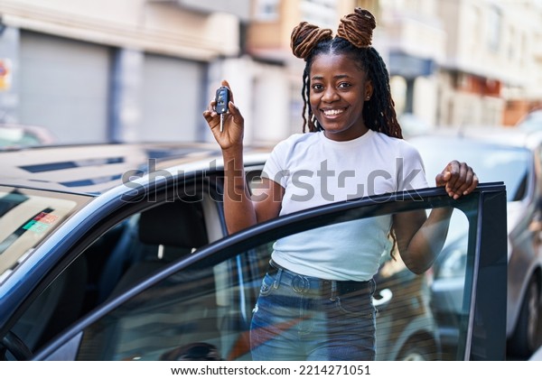 African american woman smiling confident holding\
key of new car at\
street