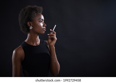 African American Woman Smoking Cigarette At Black Background.