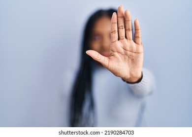 African american woman standing over blue background doing stop sing with palm of the hand. warning expression with negative and serious gesture on the face.  - Shutterstock ID 2190284703