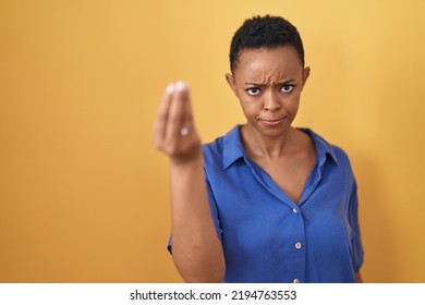 African American Woman Standing Over Yellow Background Doing Italian Gesture With Hand And Fingers Confident Expression 