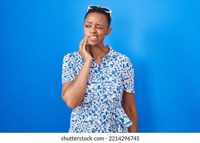 African American Woman Standing Over Blue Background Touching Mouth With Hand With Painful Expression Because Of Toothache Or Dental Illness On Teeth. Dentist 