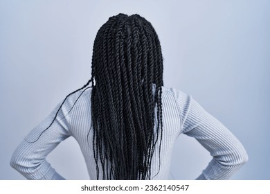 African american woman standing over blue background standing backwards looking away with arms on body  - Powered by Shutterstock