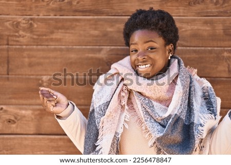 African american woman standing over wood background screaming proud, celebrating victory and success very excited with raised arm 
